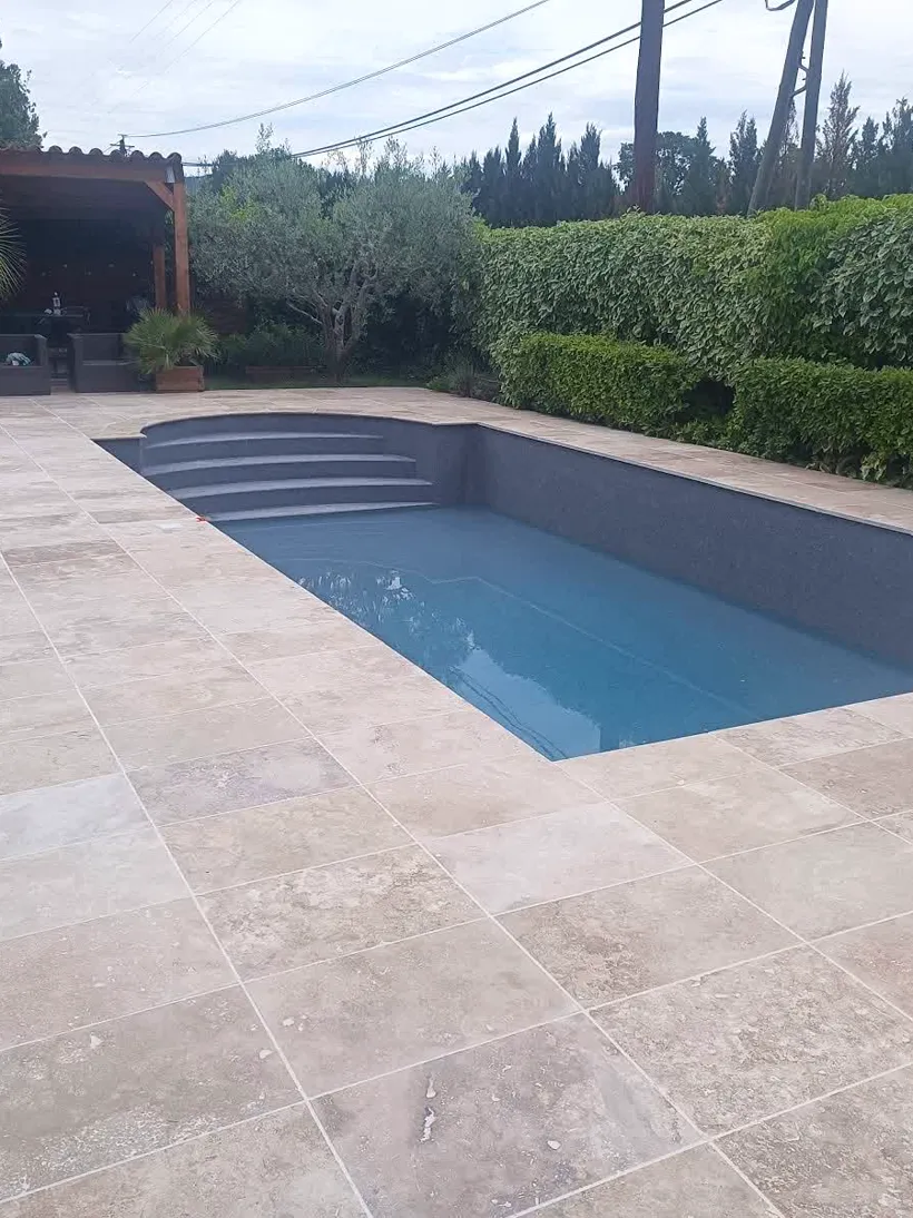 Plage de piscine en travertin avec escalier d'angle, réalisée par Kevin Lémé