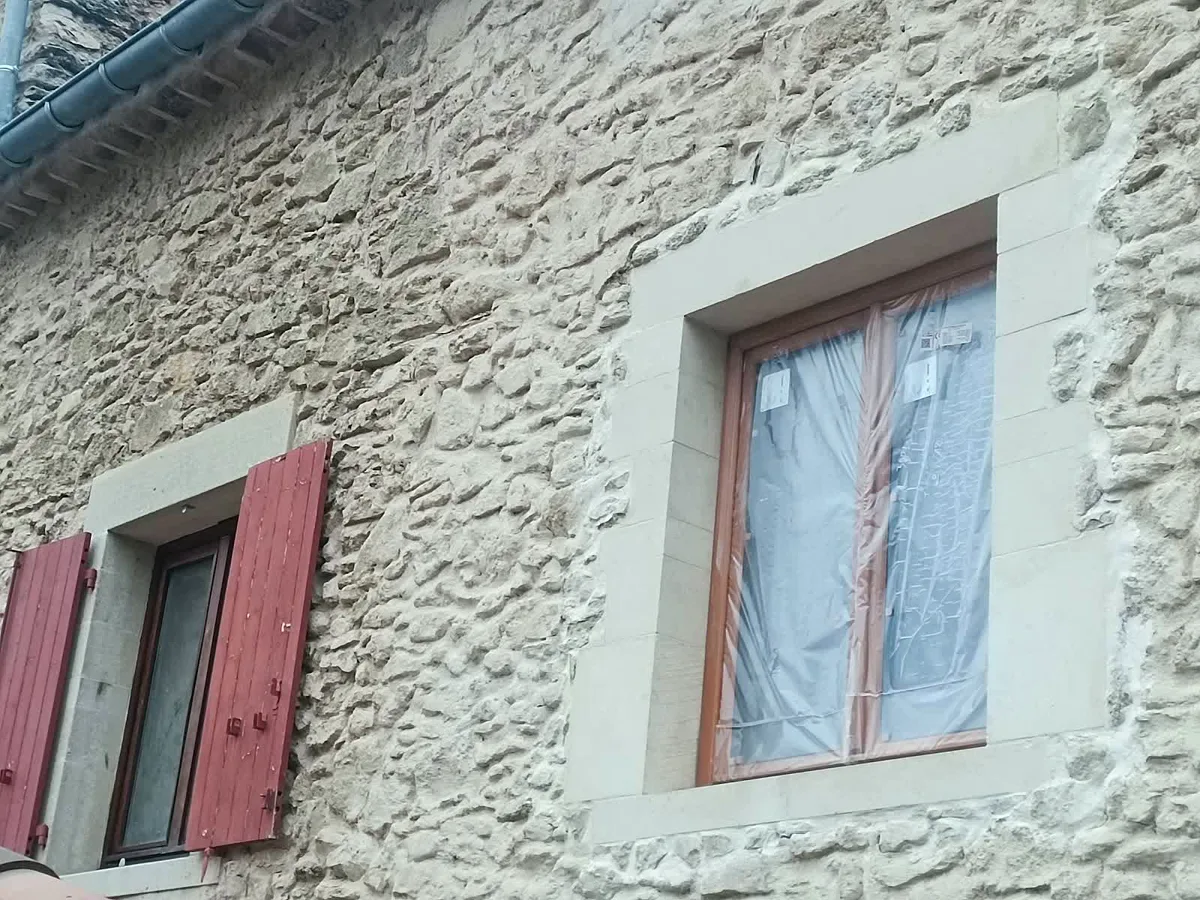Façade en pierre apparente rejointoyée, volets rouges